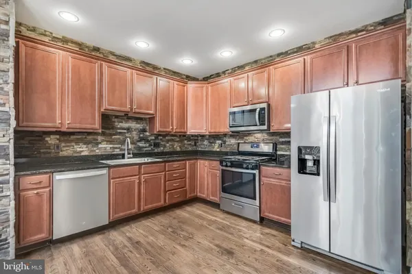 a kitchen with stainless steel appliances granite countertop a refrigerator stove a sink and dishwasher with wooden cabinets