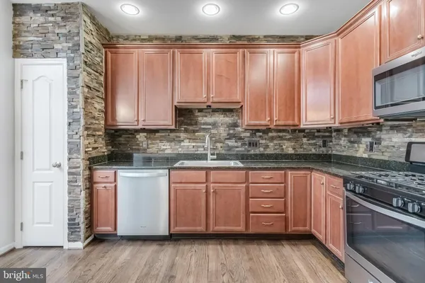 a kitchen with stainless steel appliances granite countertop a stove a sink dishwasher and cabinets with wooden floor