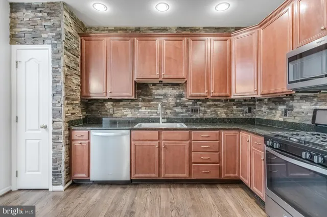 a kitchen with stainless steel appliances granite countertop a stove a sink dishwasher and cabinets with wooden floor