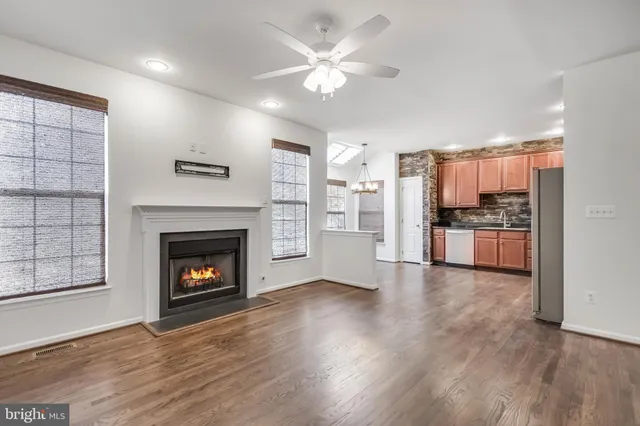 an empty room with windows fireplace and a kitchen view