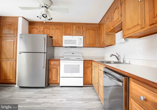 a kitchen with stainless steel appliances granite countertop a refrigerator a stove a sink and white cabinets