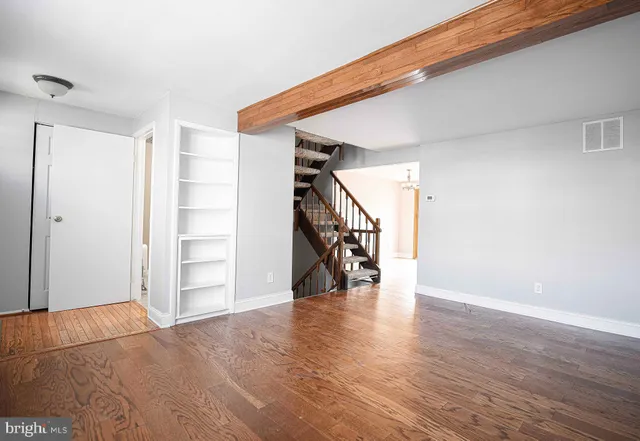 a view of an empty room with wooden floor and stairs