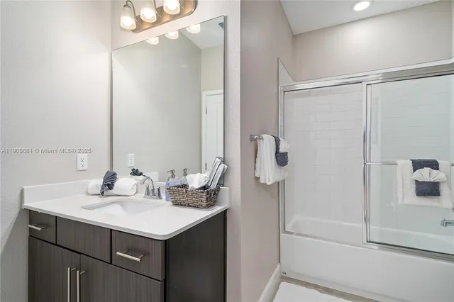 a bathroom with a sink and mirror with shower