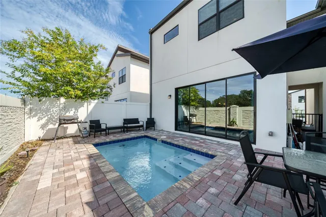 a swimming pool with barbeque oven table and chairs