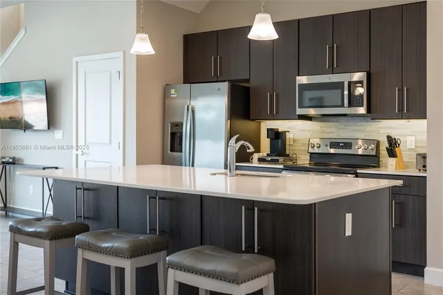 a kitchen with stainless steel appliances a sink a stove a microwave a refrigerator and cabinets