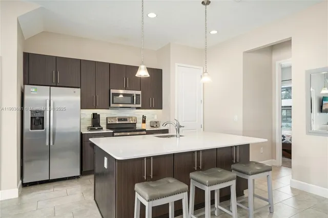 a kitchen with a refrigerator a stove a sink and chairs