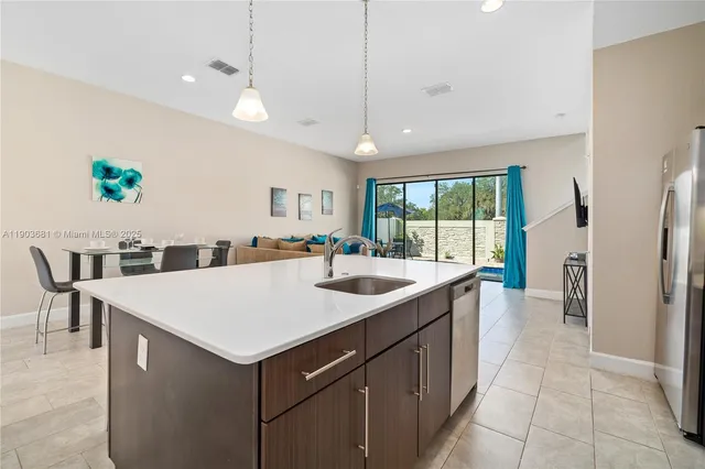 a large kitchen with kitchen island a sink a counter and a refrigerator