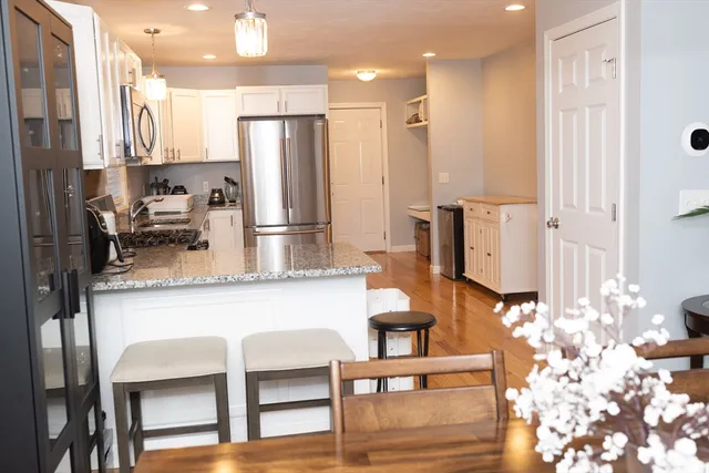 a kitchen with stainless steel appliances kitchen island granite countertop a table chairs and a refrigerator