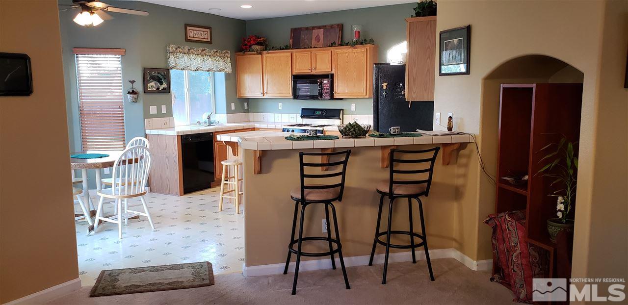 723 Silver Mine Court Reno, NV 89521 - Photo 4 of 17 a kitchen with stainless steel appliances granite countertop a stove top oven a sink a dining table and chairs with wooden floor
