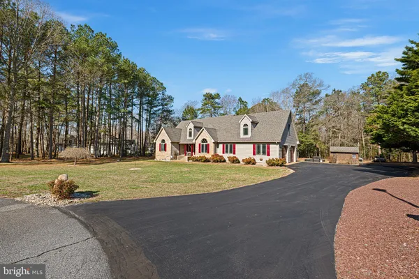 a front view of a house with a big yard and large trees