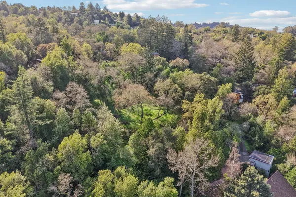 an aerial view of a houses with a lush green hillside