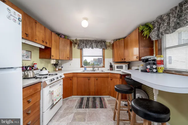 a kitchen with stainless steel appliances a sink a stove a refrigerator cabinets and a window