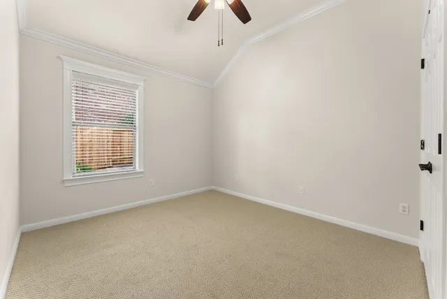 an empty room with chandelier fan and windows