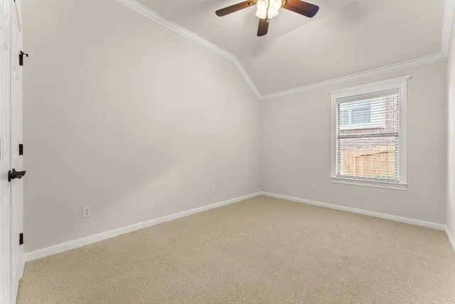 an empty room with a chandelier fan and windows
