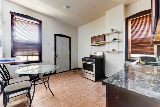 a kitchen with stainless steel appliances kitchen island granite countertop a table chairs and a refrigerator