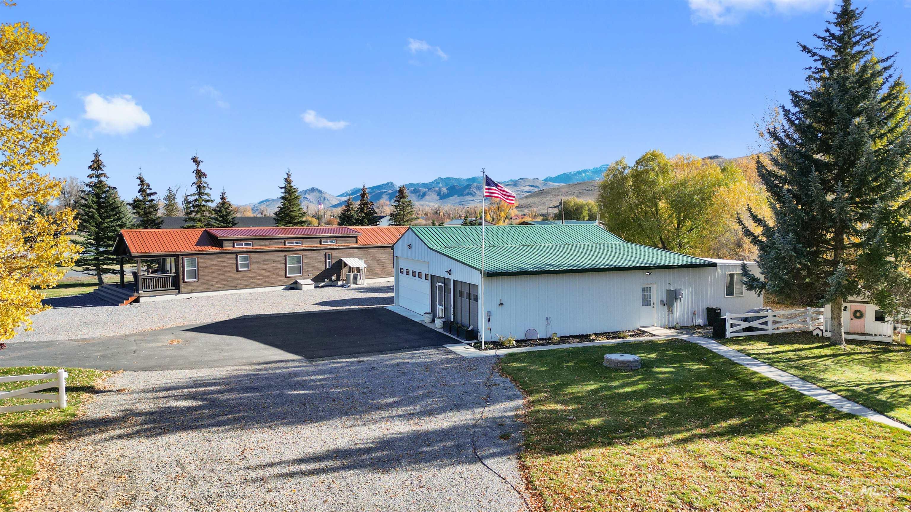 107 Willow Street Mackay, ID 83251 - Photo 9 of 48 View of property exterior with a metal roof, a garage, a mountain view, and a yard