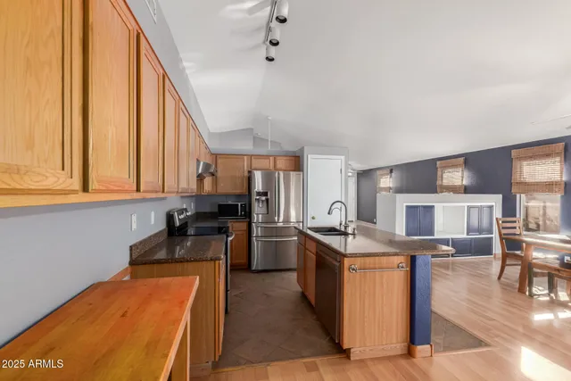 a kitchen with stainless steel appliances granite countertop a stove top oven a sink dishwasher and cabinets with wooden floor