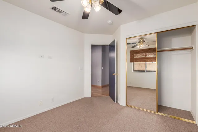 an empty room with closet and a ceiling fan