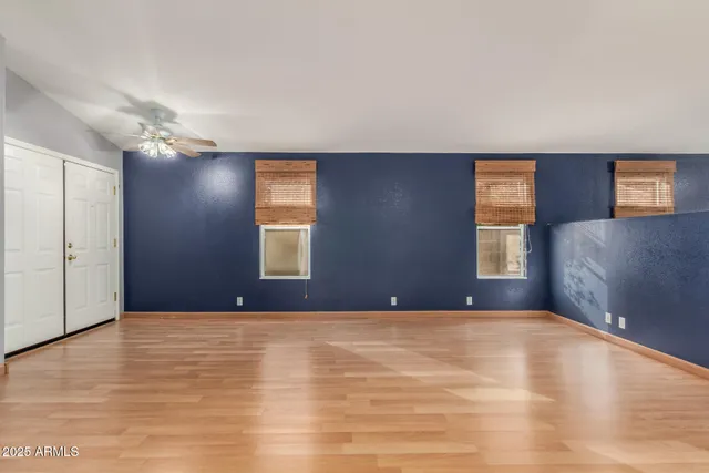 a view of an empty room with window and chandelier fan