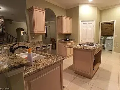 a kitchen with kitchen island granite countertop a sink stove and cabinets