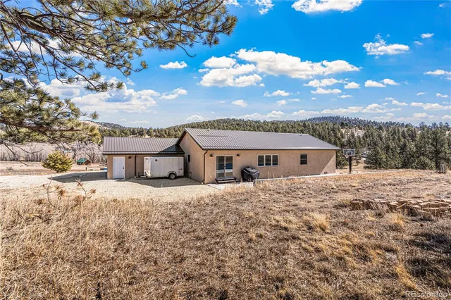 a front view of a house with a yard and mountain view in back