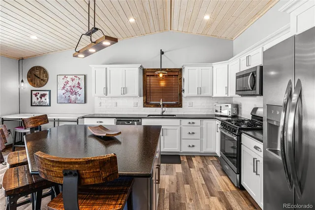 a kitchen with stainless steel appliances granite countertop a stove a refrigerator a sink a dining table and chairs with wooden floor