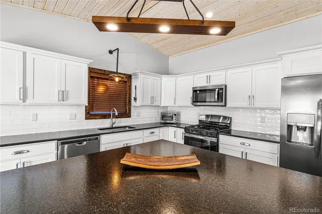a kitchen with stainless steel appliances a stove a sink and white cabinets