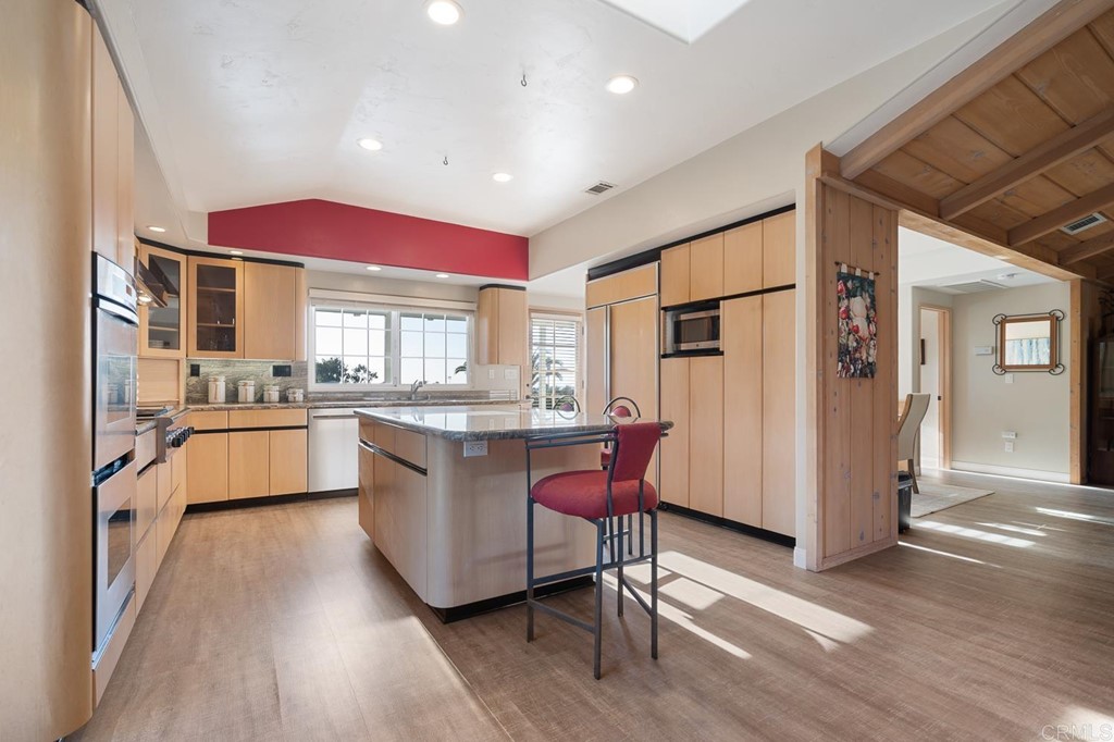 1754 Crest Drive Encinitas, CA 92024 - Photo 13 of 43 a kitchen with granite countertop a refrigerator a sink dishwasher a stove top oven a dining table and chairs with wooden floor