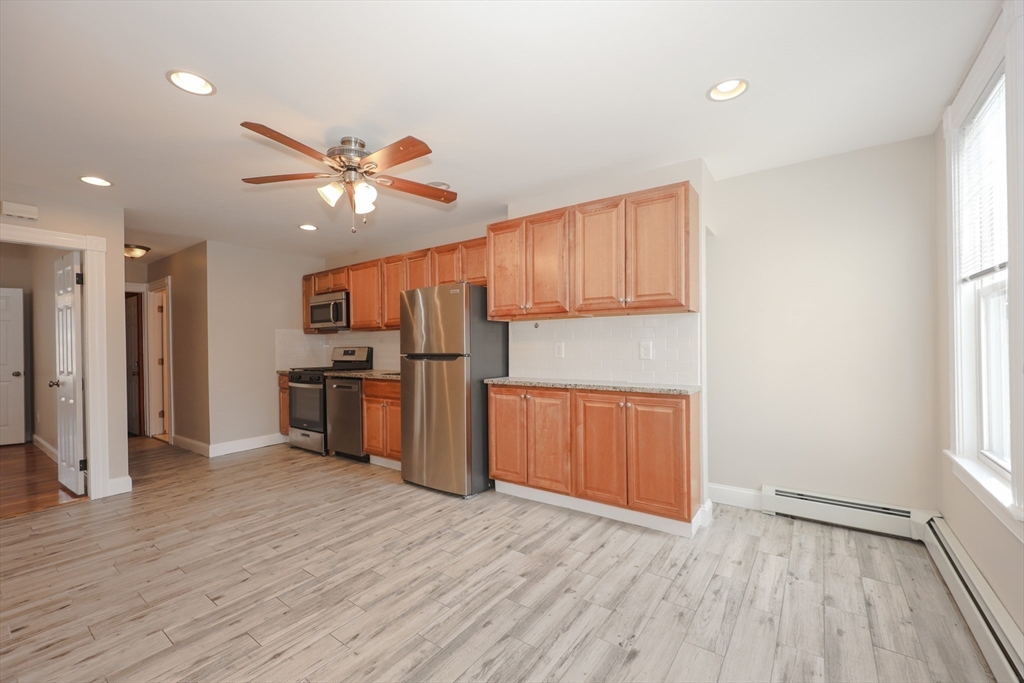 64 Bremen Street, Unit 3 Boston, MA 02128 - Photo 2 of 16 a kitchen with stainless steel appliances kitchen island wooden floors and wooden cabinets