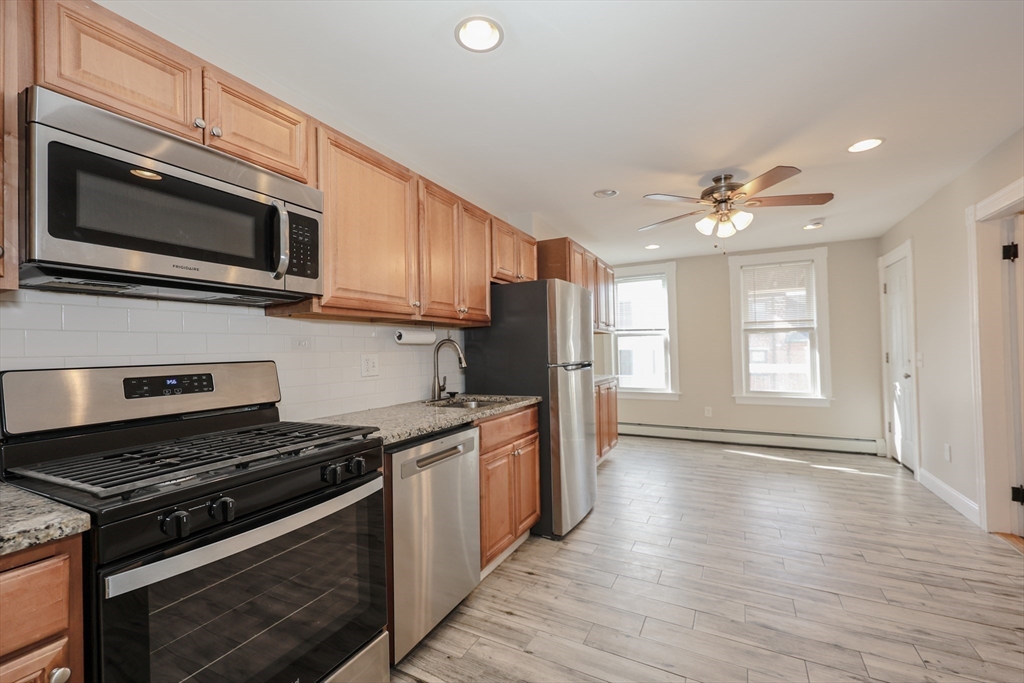 64 Bremen Street, Unit 3 Boston, MA 02128 - Photo 3 of 16 a kitchen with stainless steel appliances granite countertop a stove top oven microwave and cabinets