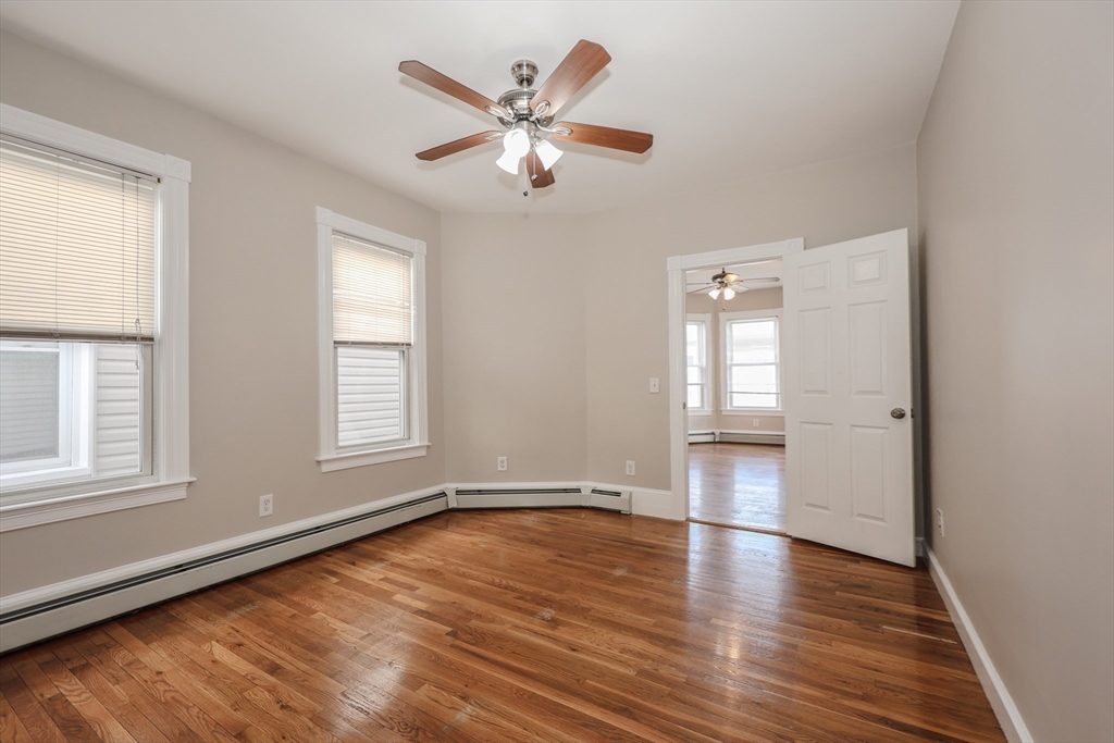 64 Bremen Street, Unit 3 Boston, MA 02128 - Photo 5 of 16 an empty room with wooden floor chandelier fan and windows