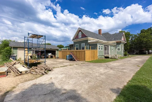 a view of a house with a yard and large tree