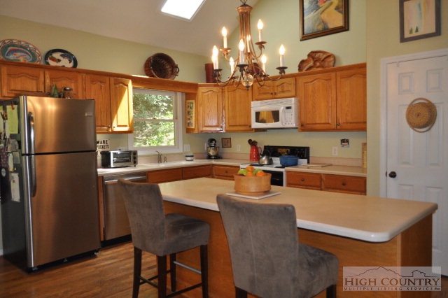 751 Pine Hill Road Boone, NC 28607 - Photo 3 of 27 a kitchen with stainless steel appliances granite countertop a refrigerator a sink a stove and a dining table with wooden floor