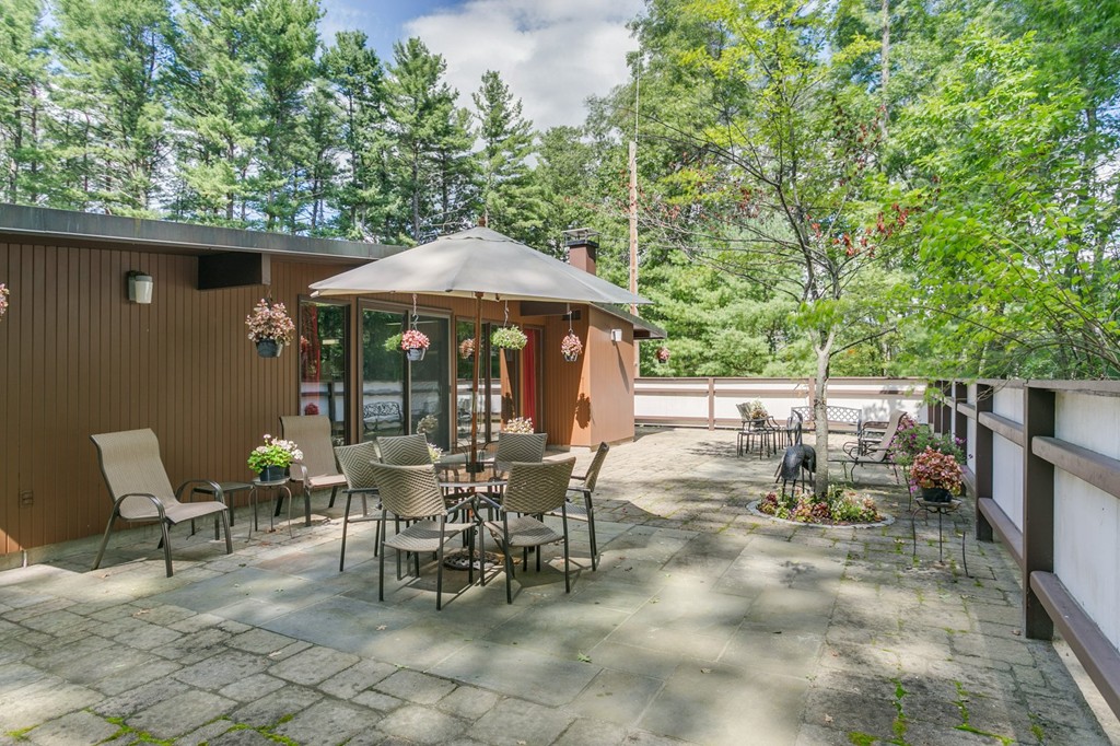 27 Conant Road Lincoln, MA 01773 - Photo 14 of 16 a view of a tables and chairs under an umbrella in backyard