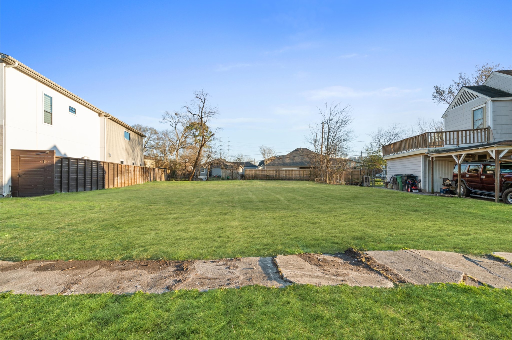 6919 Burgess Street Houston, TX 77021 - Photo 7 of 12 Spacious, grassy lot with a clear, open area perfect for development. The property is bordered by fences and neighboring homes, offering a mix of privacy and community atmosphere. Ideal for building a custom home or investment property.