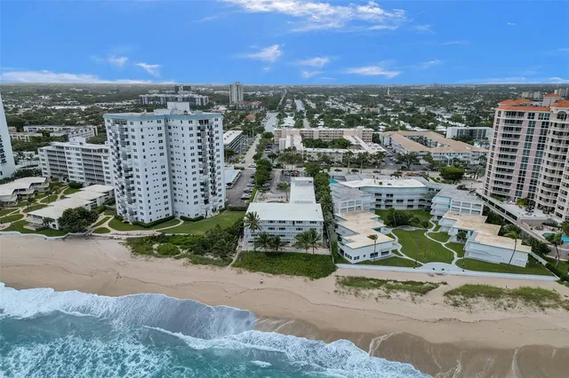 an aerial view of residential houses with outdoor space and ocean view
