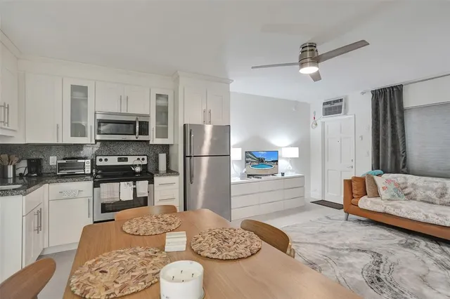 a kitchen with stainless steel appliances kitchen island granite countertop a stove a sink a microwave a dining table and chairs with white cabinets
