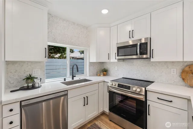 a kitchen with granite countertop a sink stainless steel appliances and cabinets