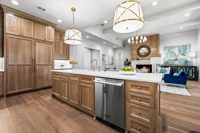 a kitchen with stainless steel appliances granite countertop a stove a sink dishwasher a refrigerator and a fireplace with wooden floor