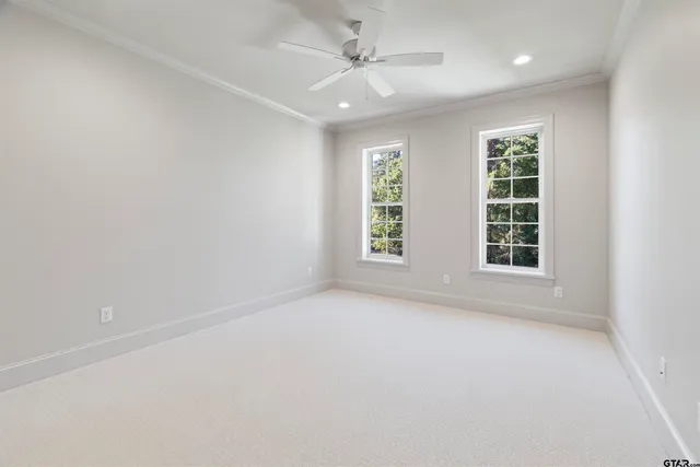 an empty room with windows and ceiling fan