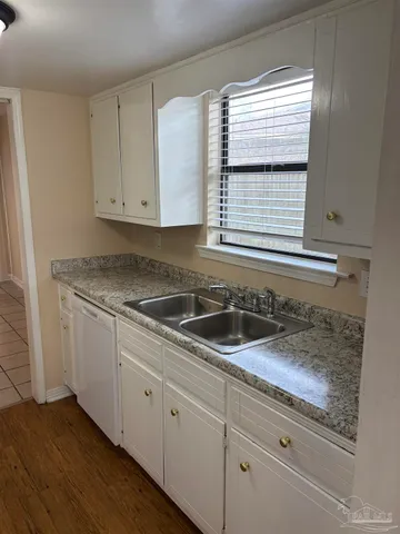 a kitchen with granite countertop white cabinets and a sink
