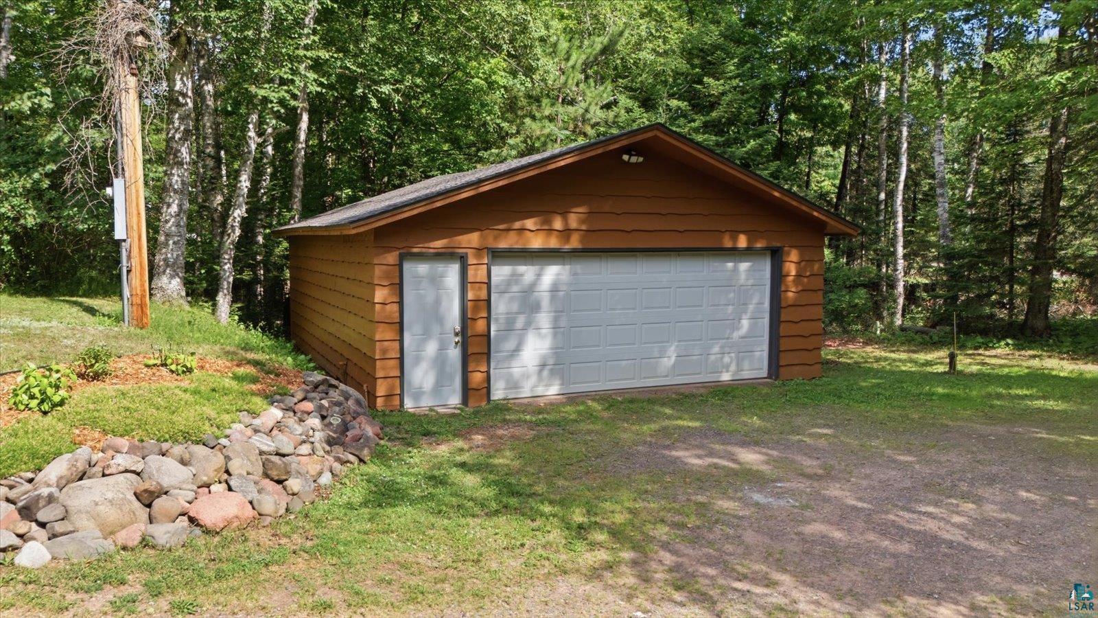 6377 Bergstrom Road Saginaw, MN 55779 - Photo 16 of 20 Detached garage with tan horizontal siding, white panel garage door, and a single white entry door