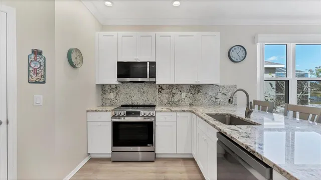 a kitchen with granite countertop a sink stainless steel appliances and cabinets