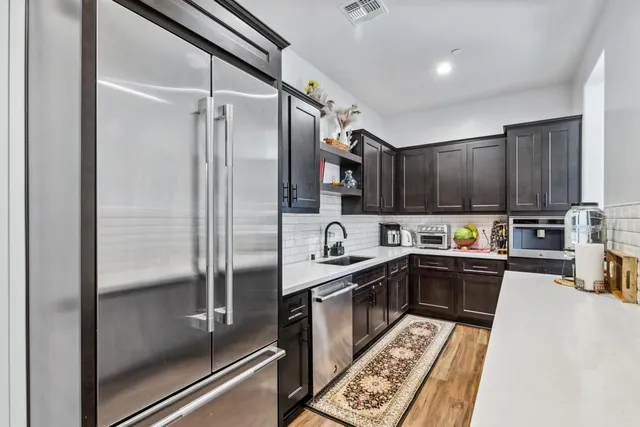 a kitchen with granite countertop a refrigerator a sink and wooden cabinets