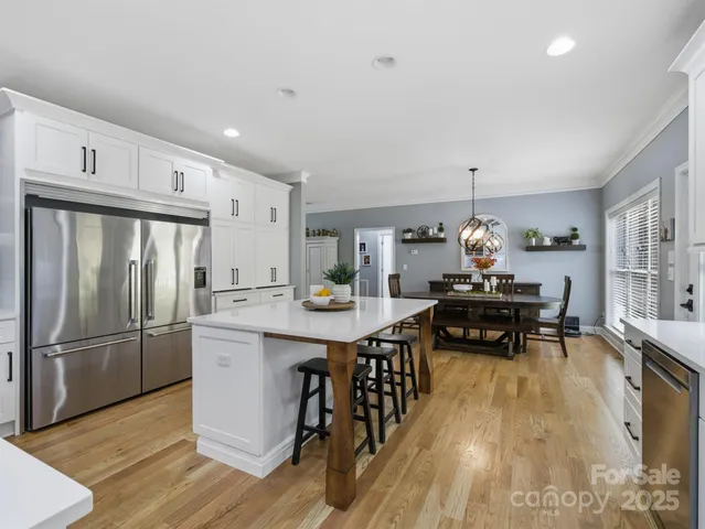 a kitchen with stainless steel appliances a sink a stove a refrigerator cabinets and dining table