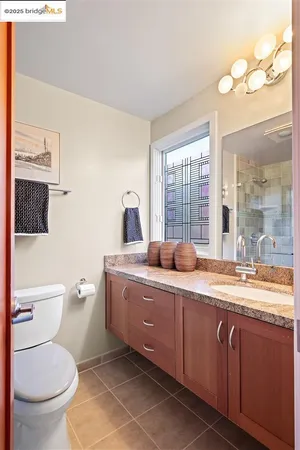a bathroom with a granite countertop toilet sink and mirror