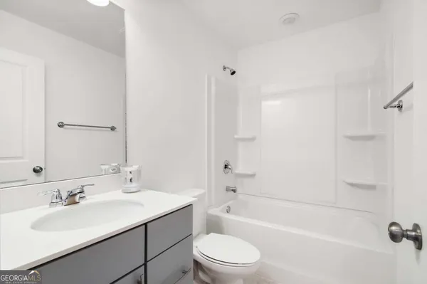 a bathroom with a bathtub shower sink vanity mirror and toilet