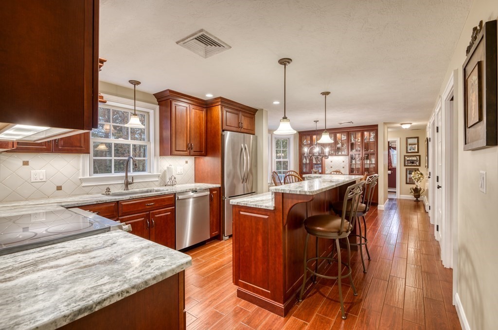 20 Clark Circle Hanover, MA 02339 - Photo 4 of 35 a kitchen with stainless steel appliances granite countertop a table chairs stove and refrigerator