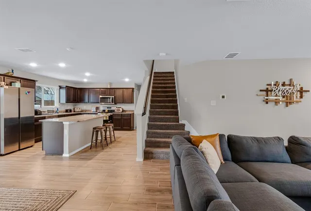a living room with furniture kitchen view and a wooden floor