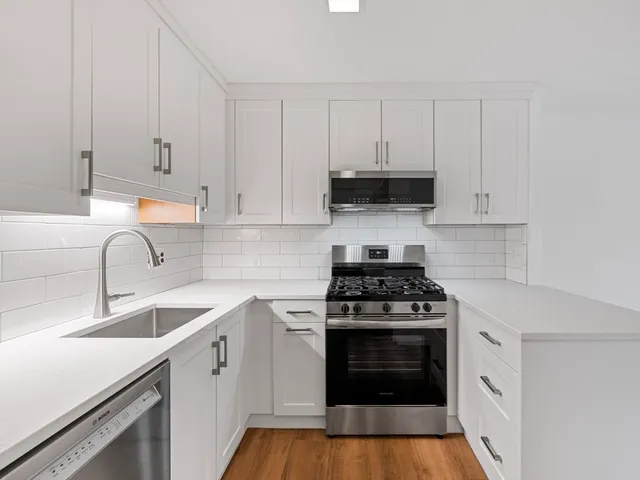 a kitchen with granite countertop white cabinets and stainless steel appliances